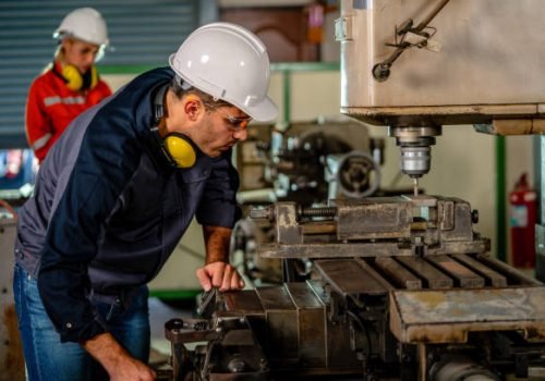 Man technician mechanic in motion of attending of work on drilling machine in factory planning