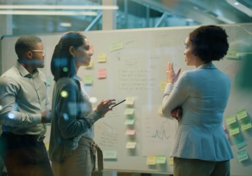 Business people, brainstorming and note on whiteboard for teamwork, planning and invest strategy in office. Data analyst, work and graph for collaboration, meeting and risk management in workplace